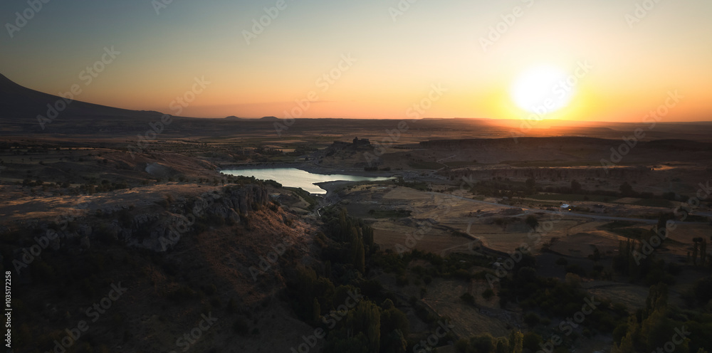 Aerial view of a serene lake at sunset with tranquil reflections and a picturesque valley, Guzelyurt, Turkey. Aerial view of a serene lake at sunset with tranquil reflections and a picturesque valley, Guzelyurt, Turkey.