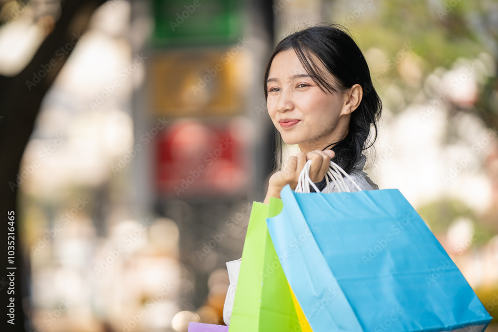 Asian woman in modern dress holding shopping bags walking outside a shopping mall. Asian woman in modern dress holding shopping bags walking outside a shopping mall.