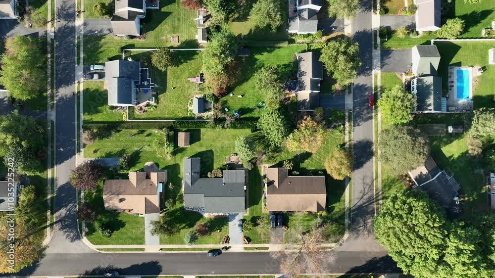 Single Family Houses in idyllic suburb of american town at sunny autumn day. Colorful trees with straight street. Modern homes with solar panels on roof. Aerial top down flyover.