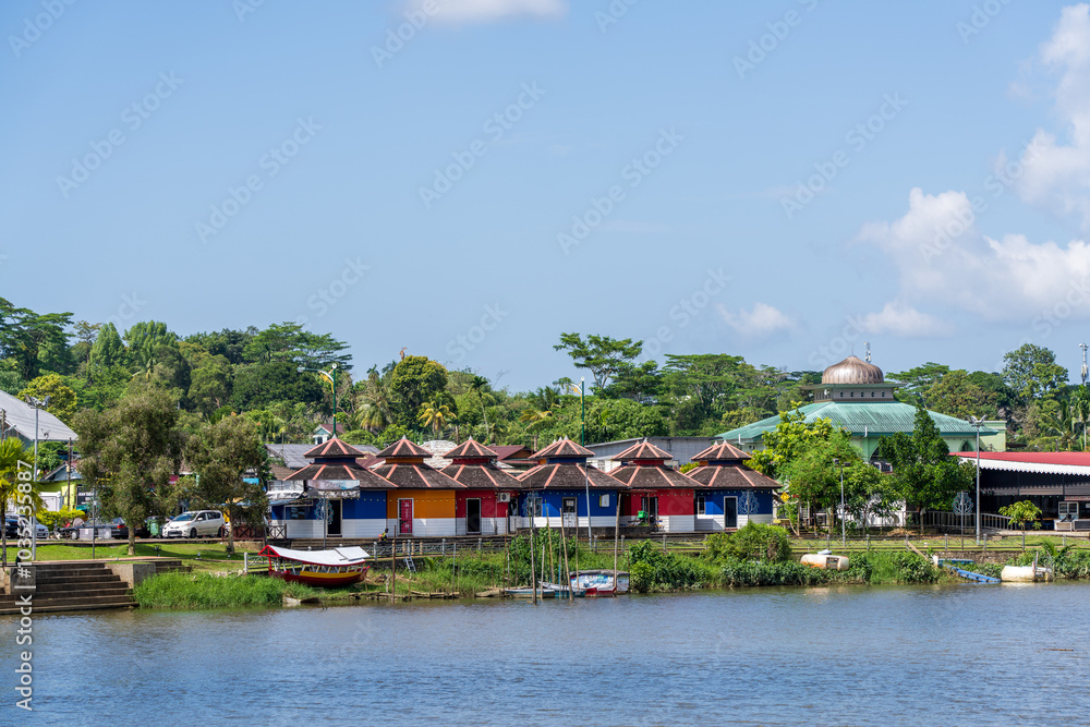 Row of identical shop front houses with pointed roof in red, orange and blue on the Sarawak River, Kuching, Malaysian Borneo. Row of identical shop front houses with pointed roof in red, orange and blue on the Sarawak River, Kuching, Malaysian Borneo.