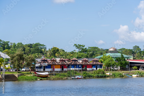 Row of identical shop front houses with pointed roof in red, orange and blue on the Sarawak River, Kuching, Malaysian Borneo.