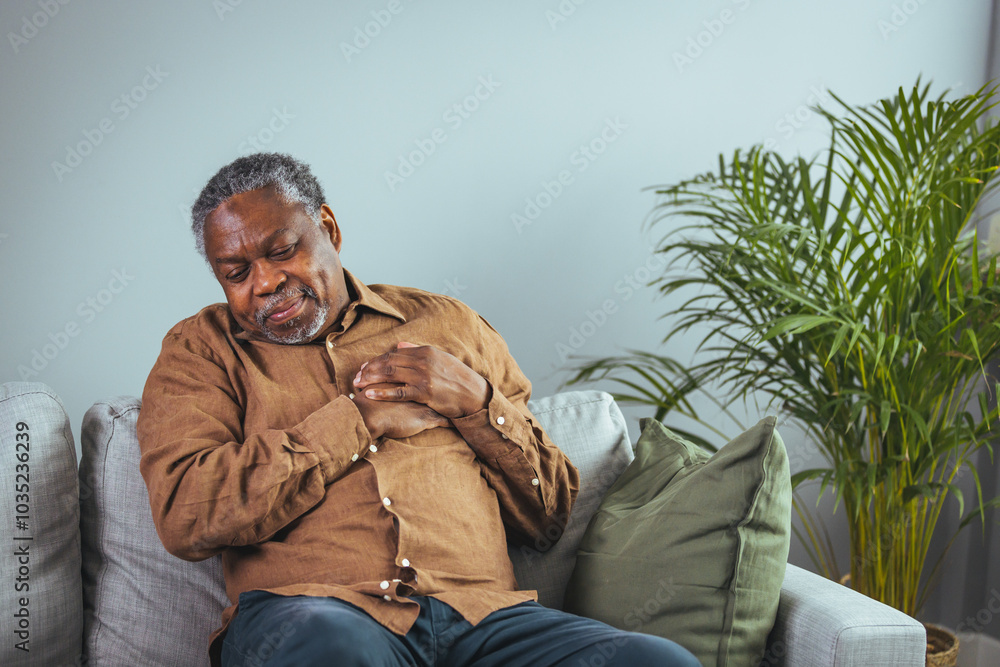 Obraz premium Senior Man Experiencing Chest Pain at Home on Sofa