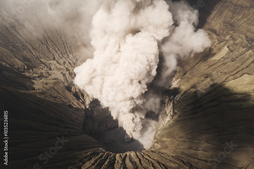 Aerial view of the active volcano with a dramatic eruption and smoky ash cloud, Sukapura, East Java, Indonesia.