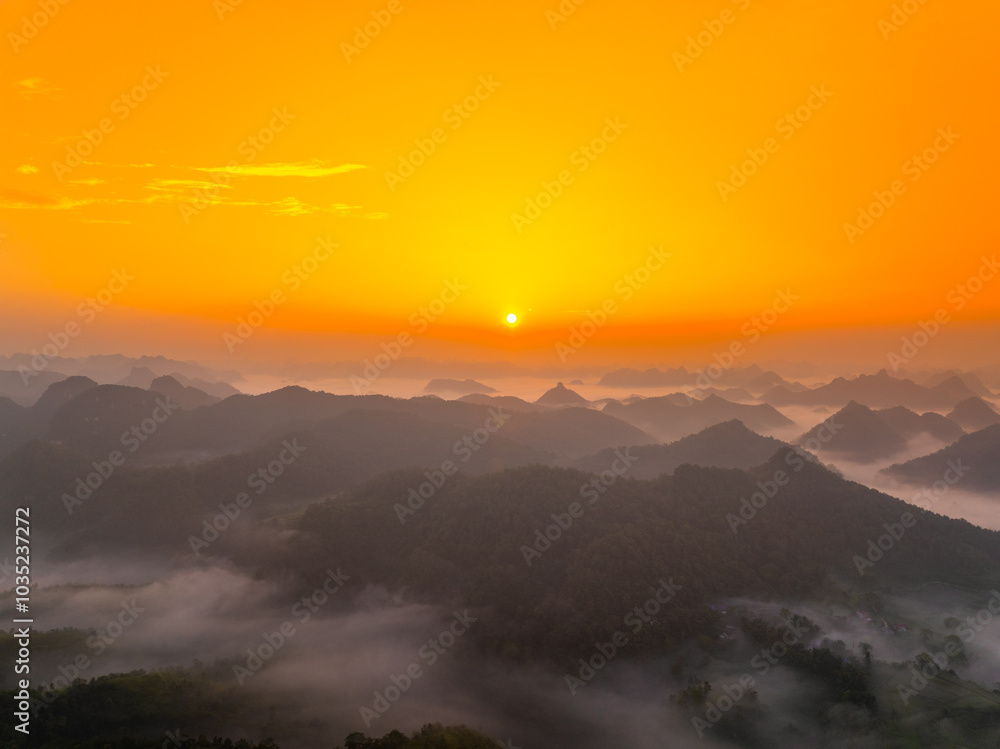 Fototapeta premium Orange sky and sea of clouds before sunrise. A peaceful, refreshing feeling. View of the hills surrounding Ba Quang, Ha Lang district, Cao Bang province, Vietnam