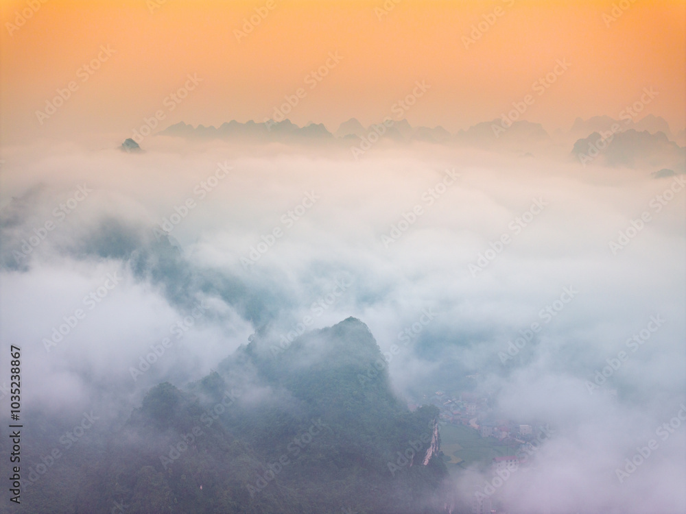 Fototapeta premium Orange sky and sea of clouds before sunrise. A peaceful, refreshing feeling. View of the hills surrounding Ba Quang, Ha Lang district, Cao Bang province, Vietnam