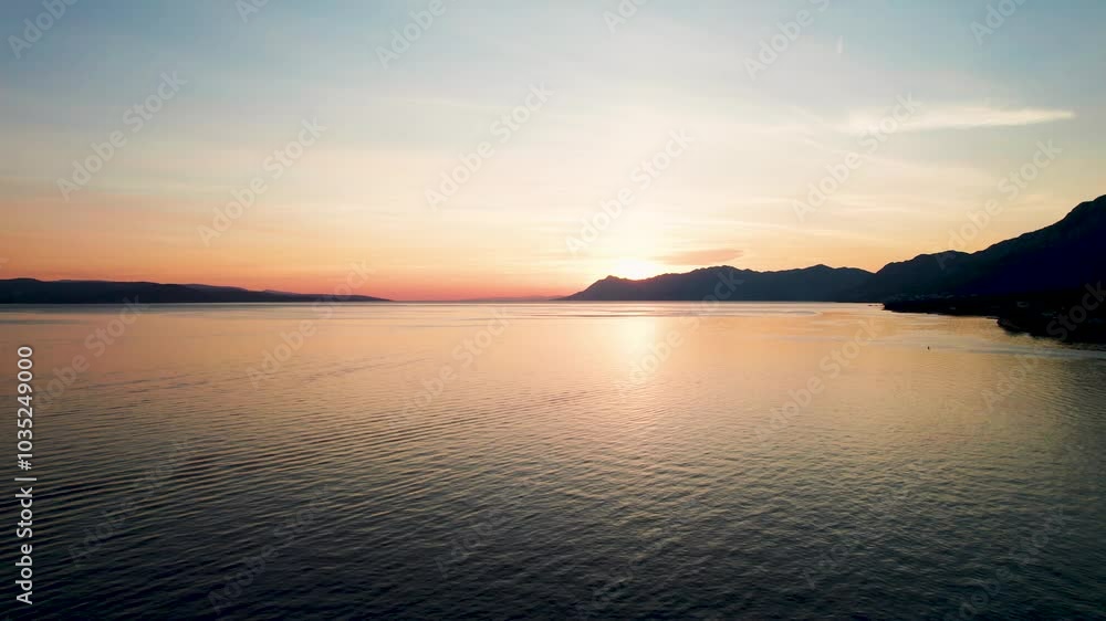 Aerial view of tranquil sunset over the azure sea with coastal mountains, Baska Voda, Croatia. Aerial view of tranquil sunset over the azure sea with coastal mountains, Baska Voda, Croatia.
