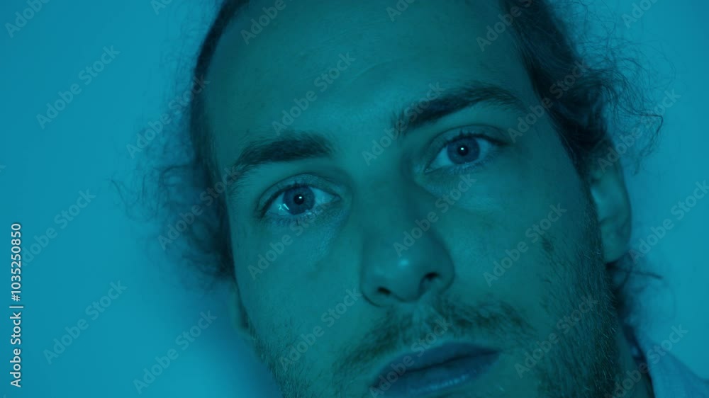 Side profile of man in blue light, quiet expression turning to look forward at angle, atmospheric soft shadows across face Side profile of man in blue light, quiet expression turning to look forward at angle, atmospheric soft shadows across face