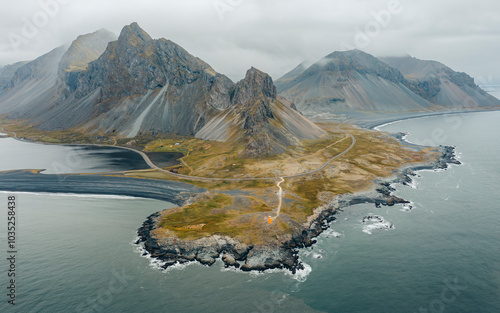 Aerial view of rugged coastline and majestic mountains under a cloudy sky, Hvalnes, Iceland. photo