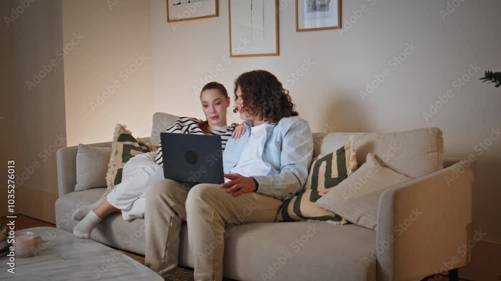 Couple discussing e-commerce store at laptop sitting comfortable apartment couch Couple discussing e-commerce store at laptop sitting comfortable apartment couch