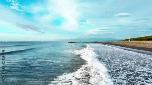 早朝の海岸に打ち寄せる穏やかなうねり。海の色が美しい。