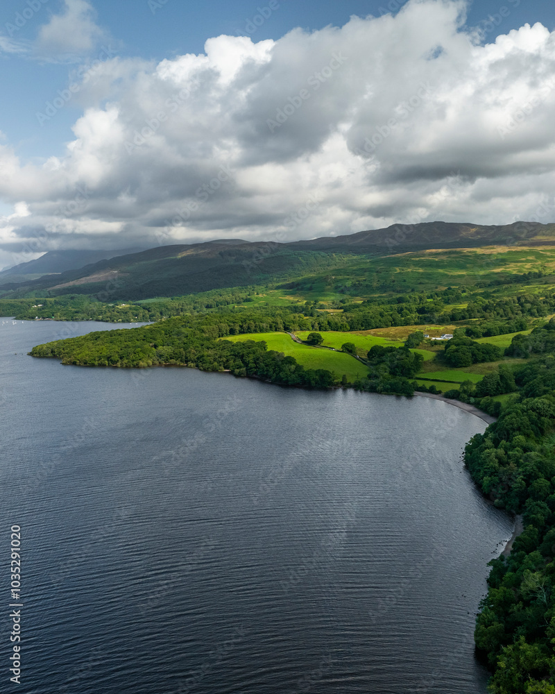 Aerial view of serene Loch Lomond surrounded by lush greenery and tranquil hills, Trossachs National Park, United Kingdom. Aerial view of serene Loch Lomond surrounded by lush greenery and tranquil hills, Trossachs National Park, United Kingdom.
