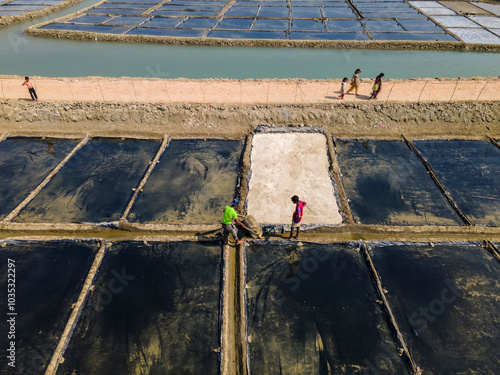 Banshkhali, Bangladesh - 06 February 2023: Aerial view of industrial salt pans with workers in a rural landscape, Banshkhali, Bangladesh. photo