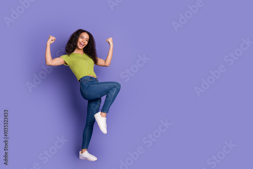 Full length photo of lovely teen lady winning raise fists dressed stylish green garment isolated on purple color background