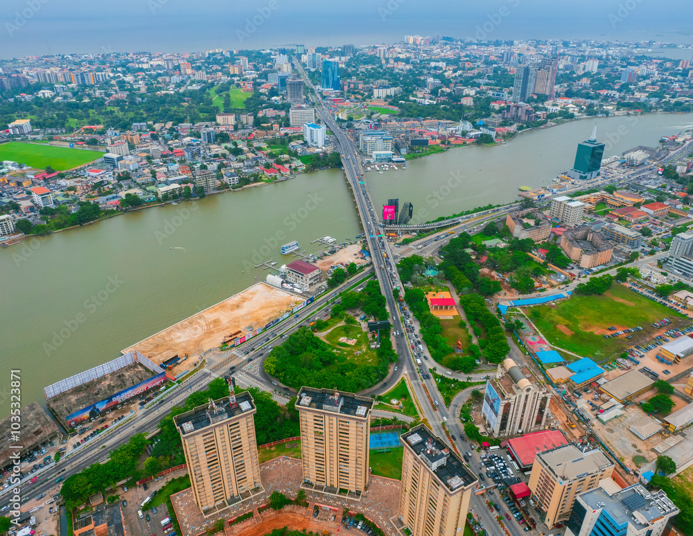 Aerial view of a bustling cityscape with modern buildings and a bridge over a river, Victoria Island, Nigeria. Aerial view of a bustling cityscape with modern buildings and a bridge over a river, Victoria Island, Nigeria.