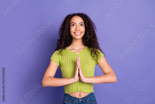 Photo portrait of lovely teen lady pray gesture look up empty space dressed stylish green garment isolated on purple color background