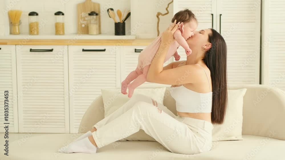 mom with a newborn baby, a young mother holds a small newborn baby in her arms, gently hugging and kissing him at home in a bright room, happy motherhood
