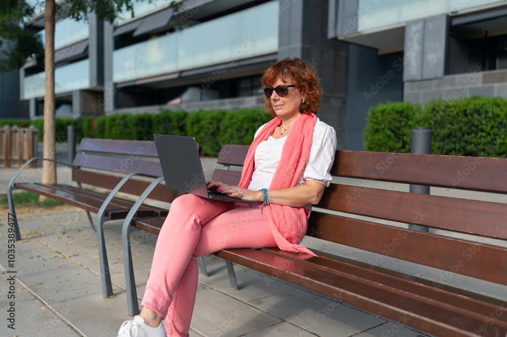 Businesswoman working on laptop sitting on bench Businesswoman working on laptop sitting on bench