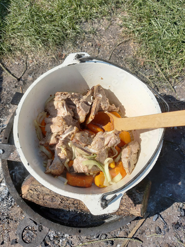 wooden spoon waving in a cauldron dish of meat and bones