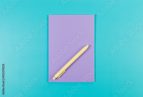 Top view of purple notebook, yellow pen on blue background. School, office wallpaper. Flat lay, copy space.