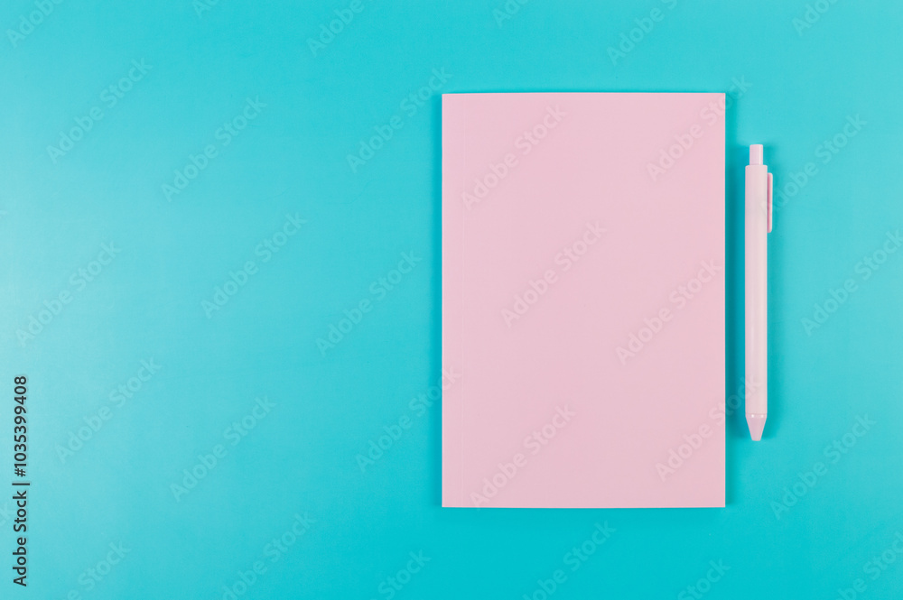 Top view of pink notebook, pink pen on blue background. School, office wallpaper. Flat lay, copy space. Top view of pink notebook, pink pen on blue background. School, office wallpaper. Flat lay, copy space.
