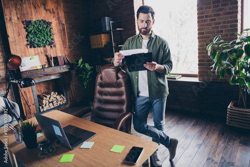 Full body photo of attractive young man read report paperholder wear green shirt comfortable modern office room interior indoors workspace photo