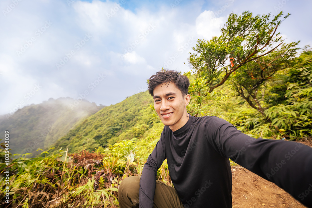 Man Embracing the Adventure, Facing Camera at Summit. Stunning Panoramic Landscape from Mountain Peak.
