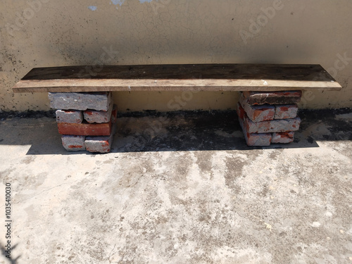 wooden plank on bricks for sitting people on this plank. These type of bench used in rural area's shops schools and houses. Wooden bench made of two pieces of tree trunks and planks. photo