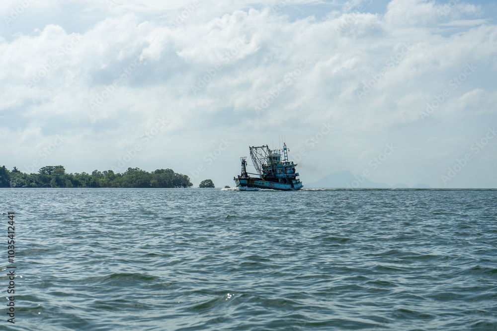 A fishing boat sails across a calm sea under a cloudy sky. A fishing boat sails across a calm sea under a cloudy sky.