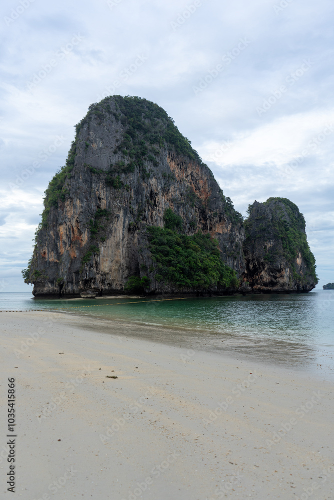Obraz premium A serene view of towering limestone cliffs by the beach.