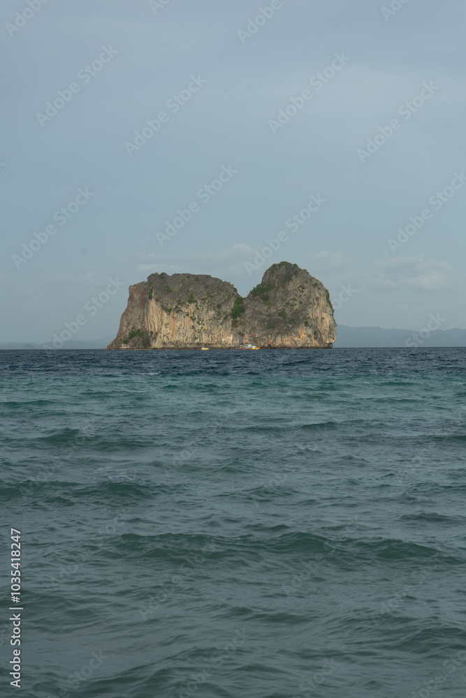 A solitary island rises from the turquoise sea under a clear sky. A solitary island rises from the turquoise sea under a clear sky.