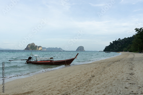 A serene beach scene with a traditional boat and distant islands.
