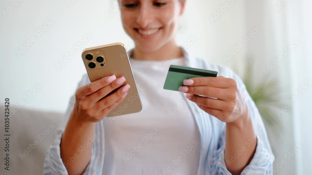 Close-up video of a mobile phone and credit card. Positive woman, holds smartphone and credit card, enter card information for online payment in a mobile app, making online shopping, smiling Close-up video of a mobile phone and credit card. Positive woman, holds smartphone and credit card, enter card information for online payment in a mobile app, making online shopping, smiling