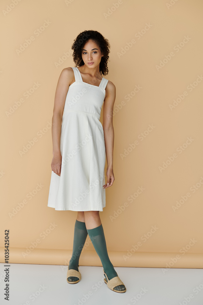 A fashionable woman showcases her chic summer outfit while striking a pose on a neutral background. A fashionable woman showcases her chic summer outfit while striking a pose on a neutral background.