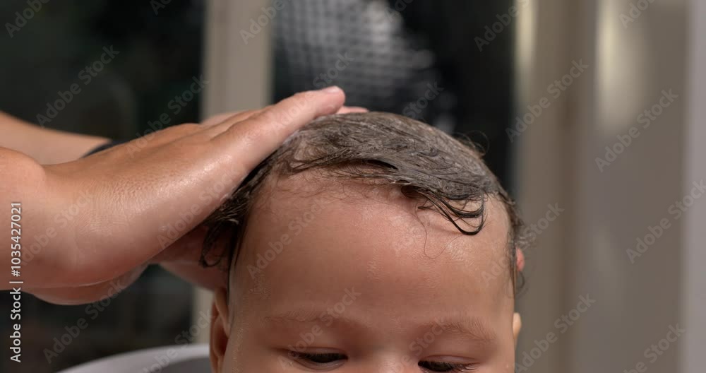 Hand placed gently over baby’s wet hair during bath, calming the baby, intimate bath care, baby with water droplets on head, relaxing bath care moment. 800 fps slow-motion Hand placed gently over baby’s wet hair during bath, calming the baby, intimate bath care, baby with water droplets on head, relaxing bath care moment. 800 fps slow-motion
