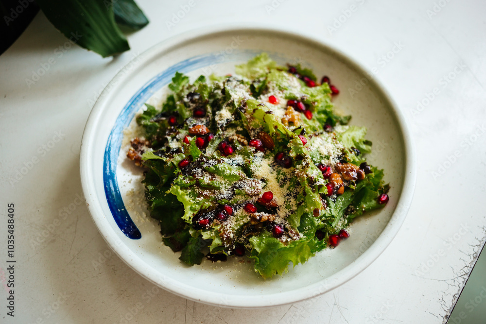 Mix of lettuce leaves with cheese on a round plate on a white table side view Mix of lettuce leaves with cheese on a round plate on a white table side view