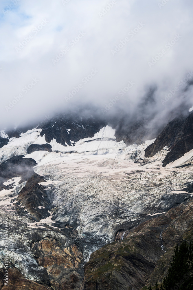 View of majestic glacier and rugged mountains under dramatic clouds, Saas Valley, Valais, Switzerland. View of majestic glacier and rugged mountains under dramatic clouds, Saas Valley, Valais, Switzerland.