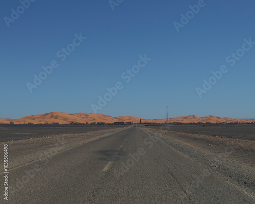 View of vast arid desert with sandy dunes and a remote highway, Merzouga, Morocco. photo