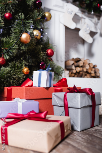 Selective focus of gift boxes near pine and fireplace with christmas stockings