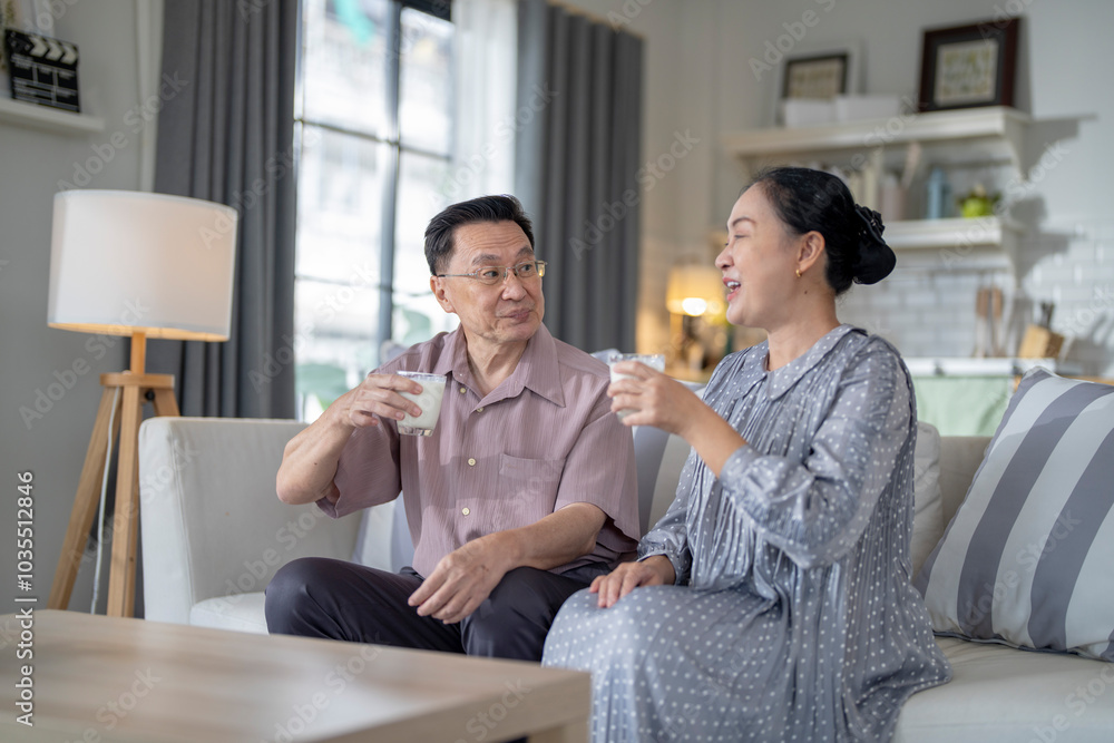 An elderly couple enjoys a peaceful moment at home, sharing smiles and drinks. The warm and cozy atmosphere emphasizes their deep connection, happiness, and the comfort of spending time together. An elderly couple enjoys a peaceful moment at home, sharing smiles and drinks. The warm and cozy atmosphere emphasizes their deep connection, happiness, and the comfort of spending time together.