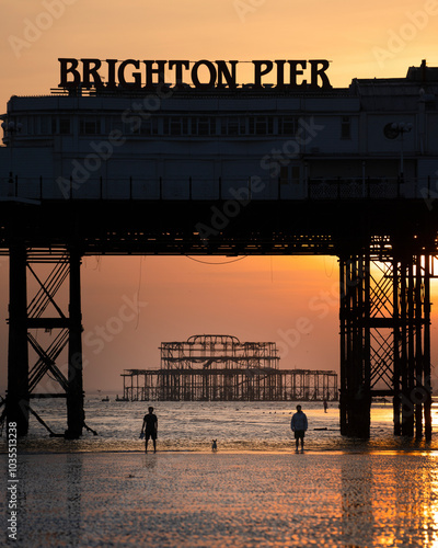 View of brighton pier at sunset with silhouettes of people, brighton, united kingdom. photo