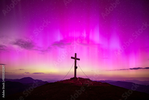 View of aurora borealis over majestic mountain peak with summit cross, Almenland, Austria. photo