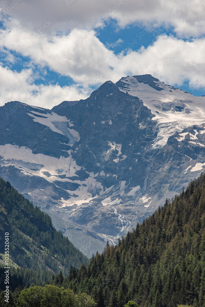 View of majestic snow-capped mountains and tranquil forests under a beautiful sky, Val Paradiso National Park, Aosta, Italy. View of majestic snow-capped mountains and tranquil forests under a beautiful sky, Val Paradiso National Park, Aosta, Italy.