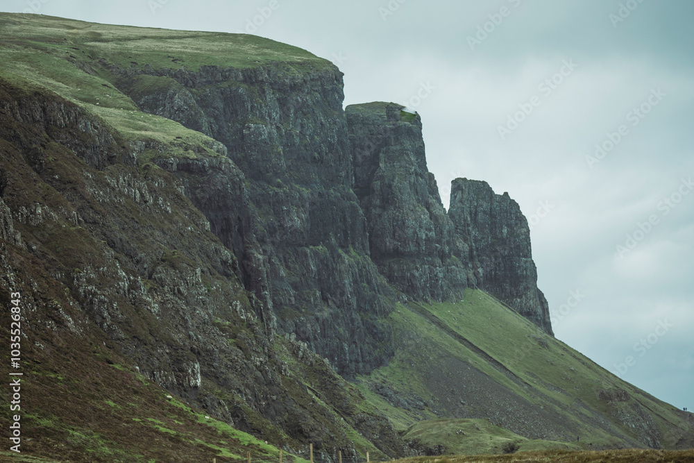 View of dramatic Quiraing rock formation on rugged cliffs surrounded by majestic mountains, Portree, Scotland. View of dramatic Quiraing rock formation on rugged cliffs surrounded by majestic mountains, Portree, Scotland.