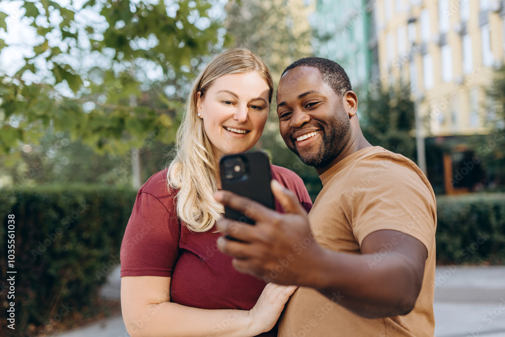 Happy young multiracial couple making selfie using smartphone outdoors Happy young multiracial couple making selfie using smartphone outdoors