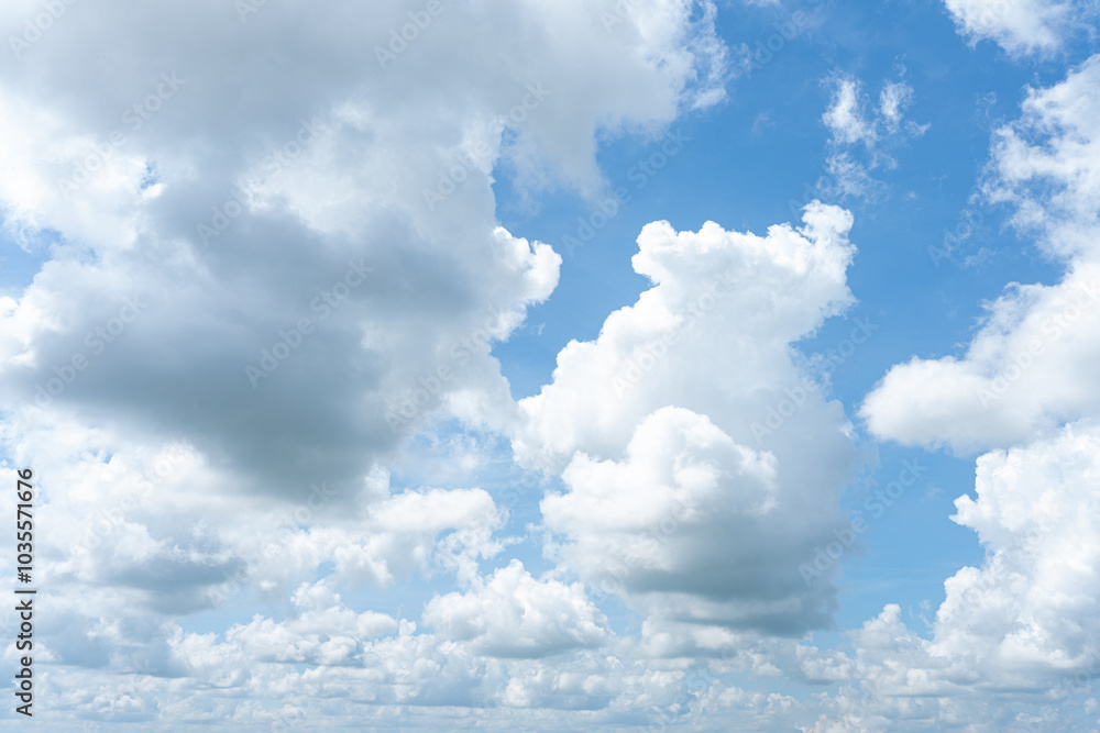 Fluffy white clouds drift across a bright blue sky, casting soft shadows on the Earth