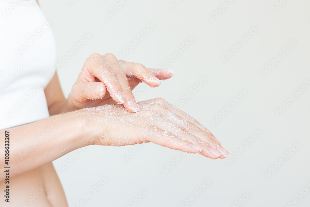 Fototapeta premium Young woman in white underwear gently applying a white sugar scrub on her hand to moisturize the skin. Body care