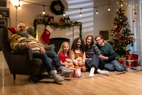 Grandfather, parents, and the teenage girls are relaxing in the living room at home on Christmas night