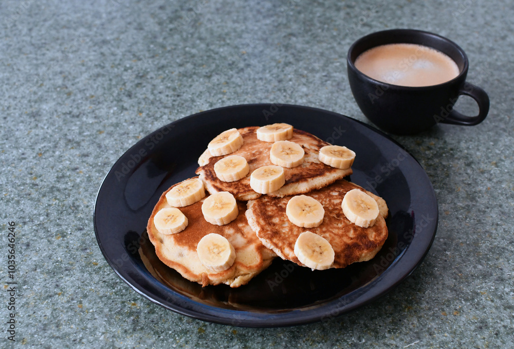 Desayuno de panqueques con banano y una taza de café. Desayuno de panqueques con banano y una taza de café.