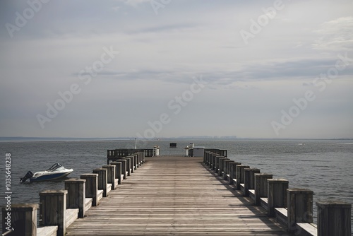 A long wooden pier extending into a body of water under an overcast sky