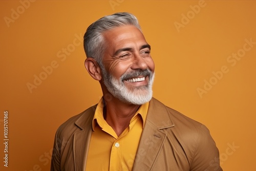 Portrait of a smiling senior man on orange background. Mature man with gray hair and beard.